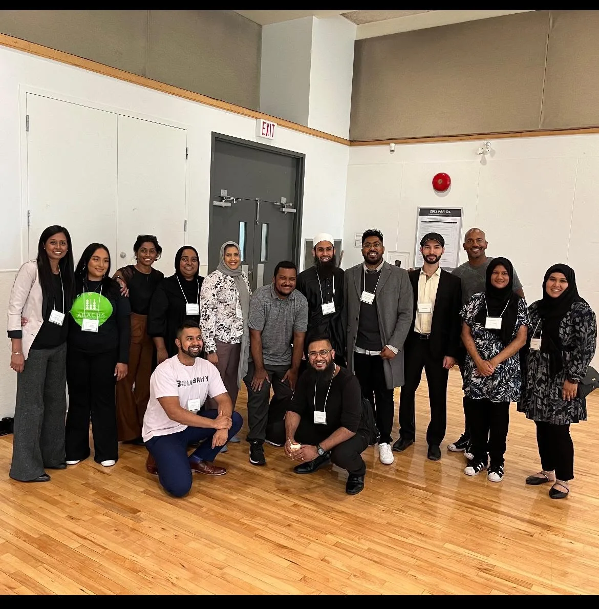 A group photo of the MCCF team, featuring board members and staff smiling together in a community hall.