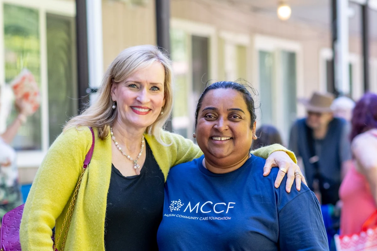 Two people at an MCCF community event, one wearing an MCCF shirt